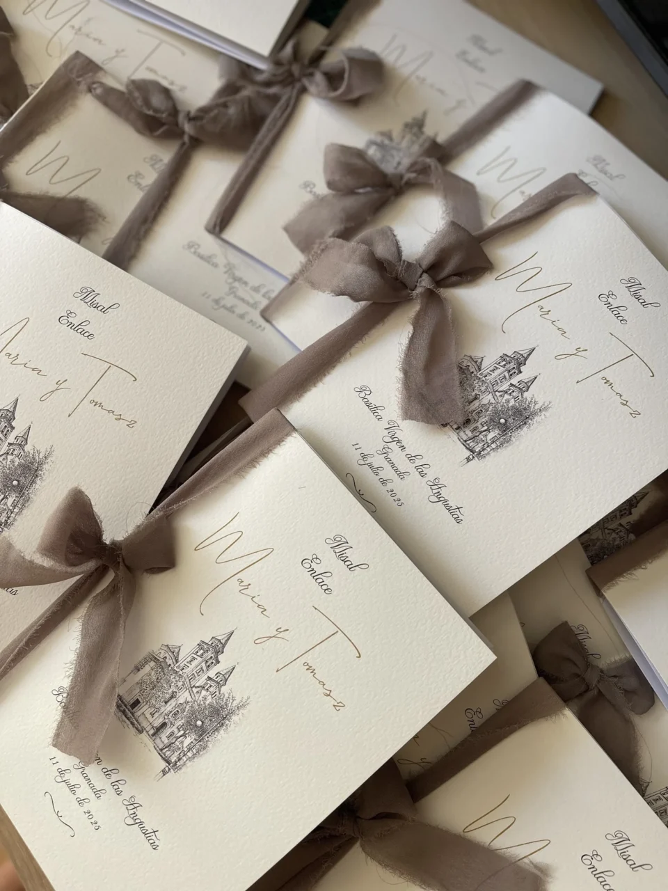Varios misales de ceremonia de María y Tomasz con portada ilustrada y lazos de tela, producidos por Pachanga Party Studio