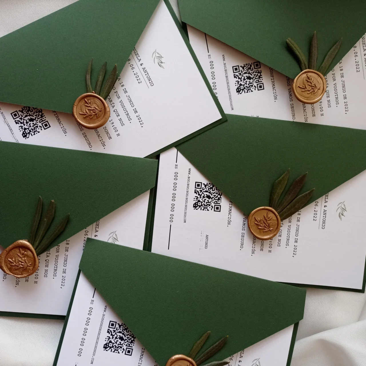 Invitaciones de boda con sobres verde oliva, sello de lacre dorado, detalles botánicos y códigos QR
