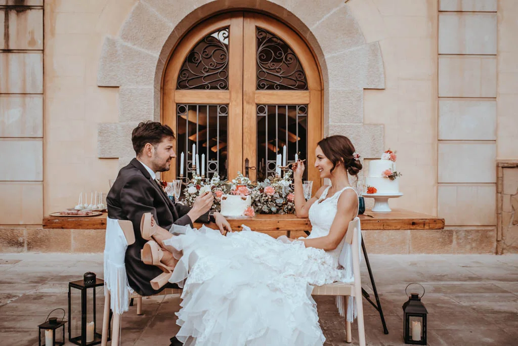 Pareja celebrando su boda sentada frente a una puerta histórica, con flores y velas